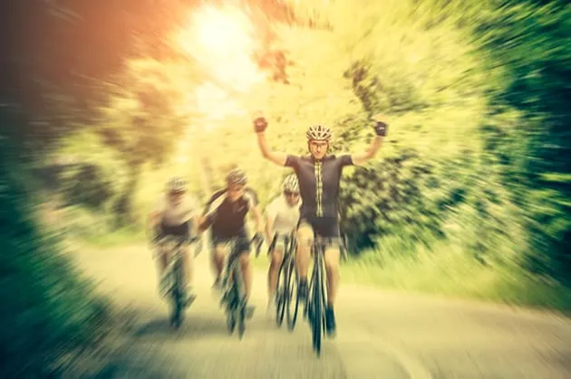 Cyclists finishing a race, the leader with both arms raised